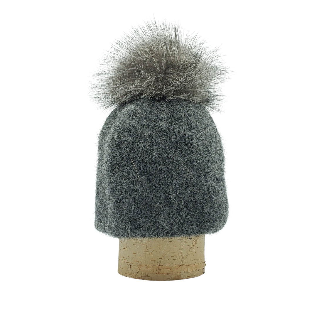 Tuque en laine islandaise grise avec un pompom gris sur une bûche par Fourrures audet