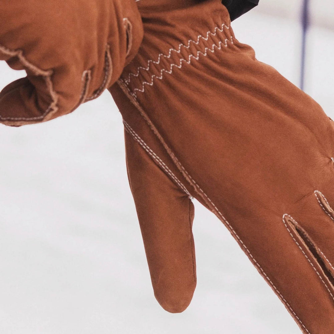 Main qui enfile des Gants en suède tan Le chasseur par Auclair