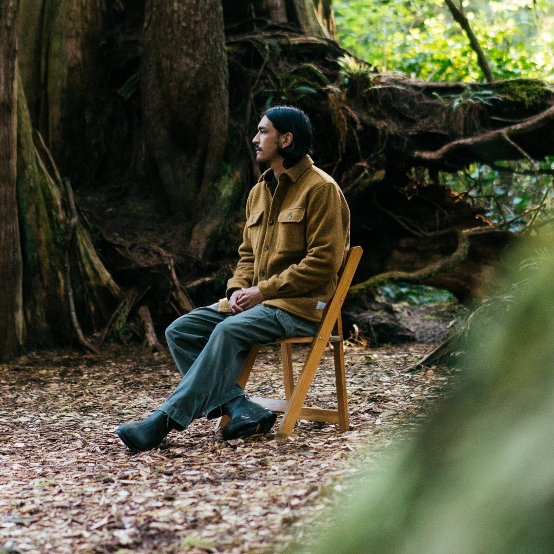 Homme portant un Manteau en laine couleur or par Anian vu de côté dans la forêt