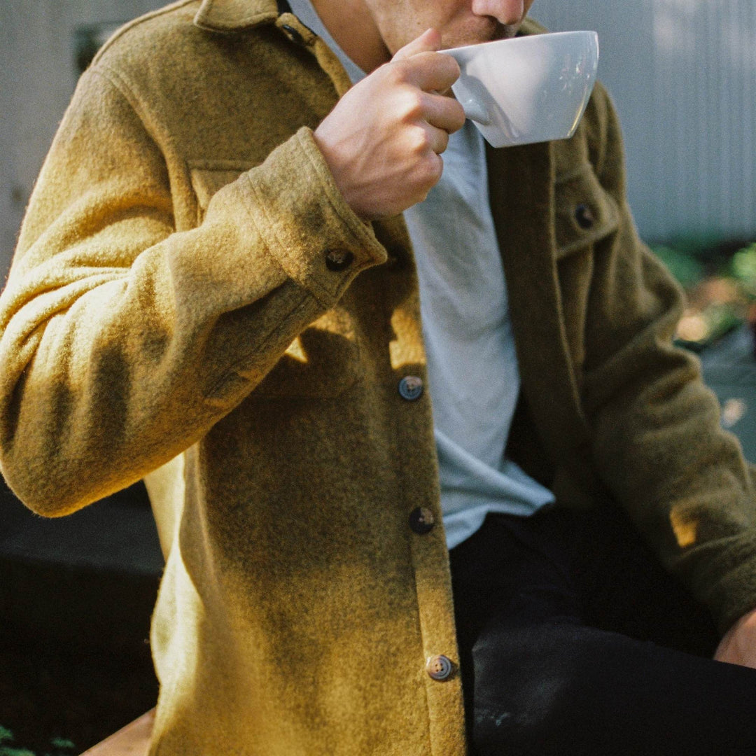 Homme portant un Manteau en laine couleur or par Anian en train de boire un café