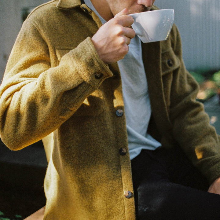 Homme portant un Manteau en laine couleur or par Anian en train de boire un café