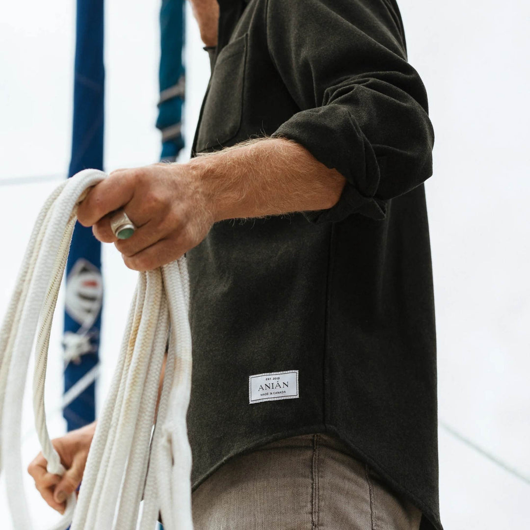 Homme sur un bateau portant un Manteau en laine molton vert par Anian vu de côté