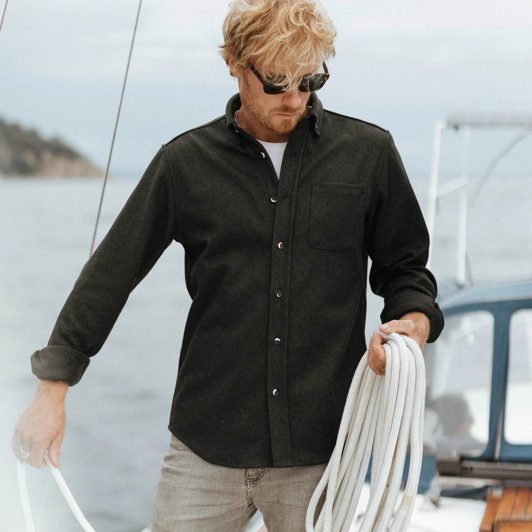 Homme sur un bateau portant un Manteau en laine molton vert par Anian