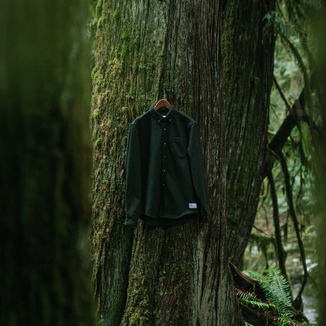 Manteau en laine molton vert par Anian accroché sur un arbre
