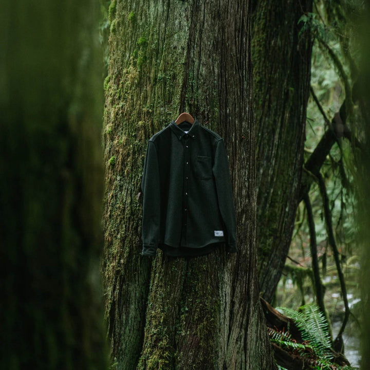 Manteau en laine molton vert par Anian accroché sur un arbre