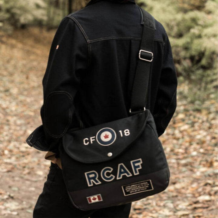 Homme portant un Sac messager RCAF CF-18 bleu par Red Canoe vu de dos