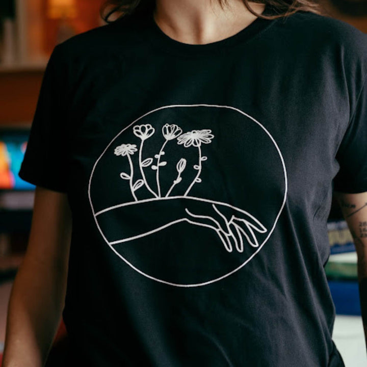 Femme portant un t-shirt noir avec une main et des fleurs comme motif par KM54