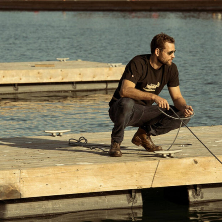Homme portant un Tshirt Norseman noir par Red Canoe sur un quaie avec une corde à bateau