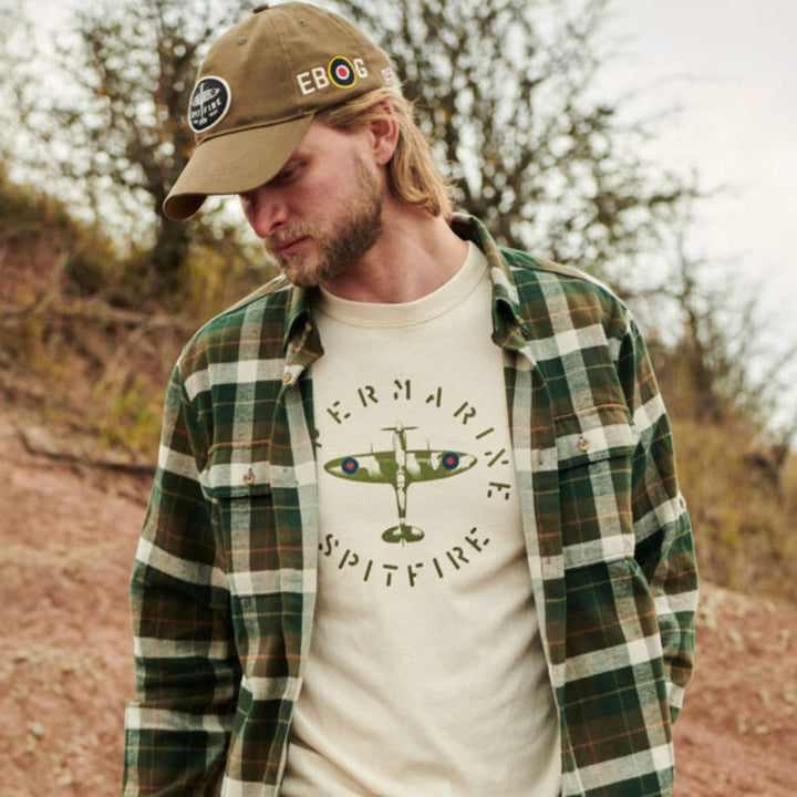 Homme regardant par terre portant un T-shirt super marine spitfire blanc et une chemise verte