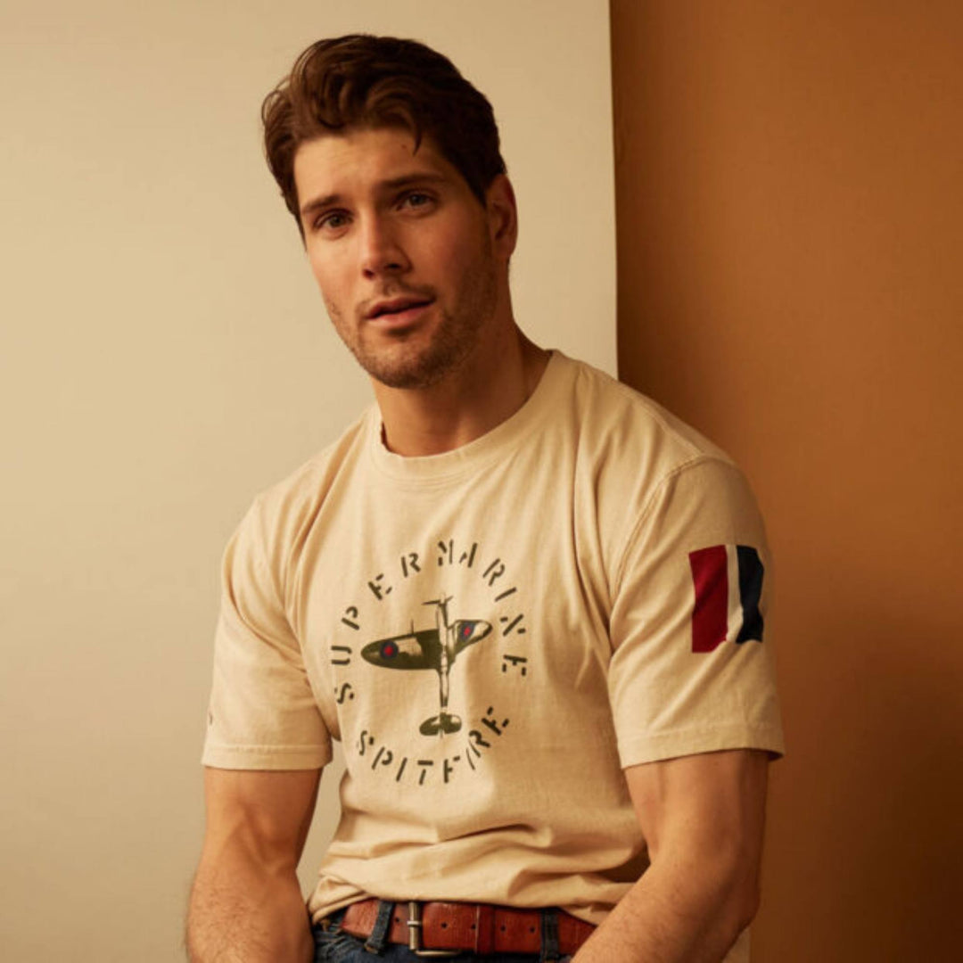 Homme assit regardant la caméra portant un T-shirt super marine spitfire blanc