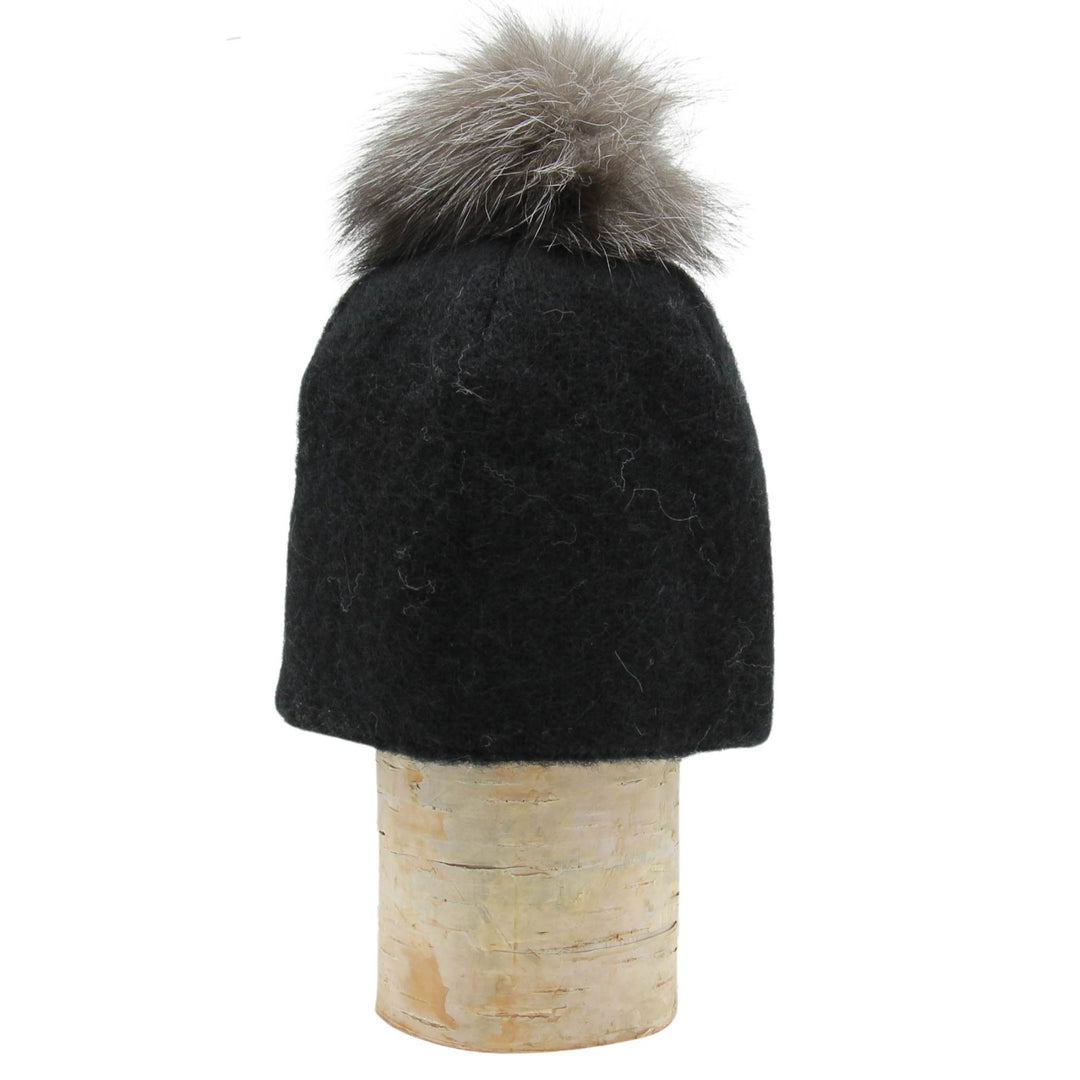 Tuque en laine islandaise noire avec un pompom gris sur une bûche par Fourrures audet