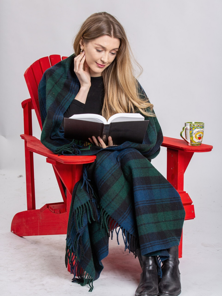 Lourde couverture tartan bleue et verte avec lignes noires sur femme lisant un livre dans une chaise rouge avec une tasse