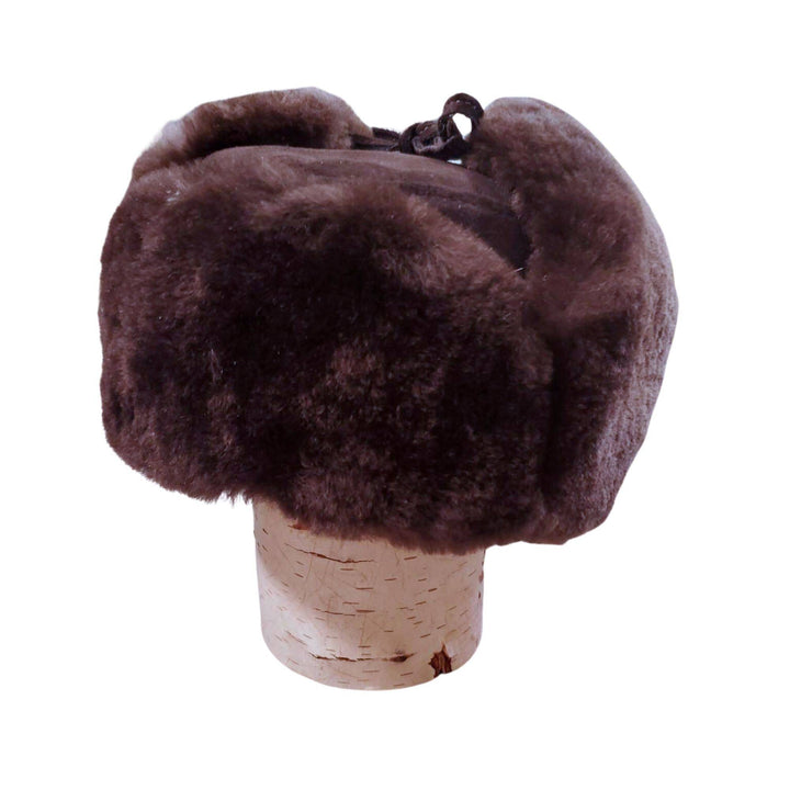 Chapeau d'hiver en castor rasé brun avec oreilles attachées sur le dessus sur une buche