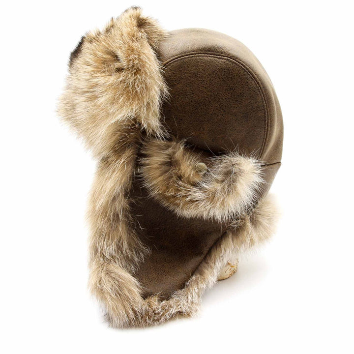 chapeau de fourrure de lynx style chapka vue de côté. le cuir est brun et on voit une oreillette avec fourrure et fourrure sur le front et intérieur des oreilles. La fourrure de lynx est de couleur beige pâle.