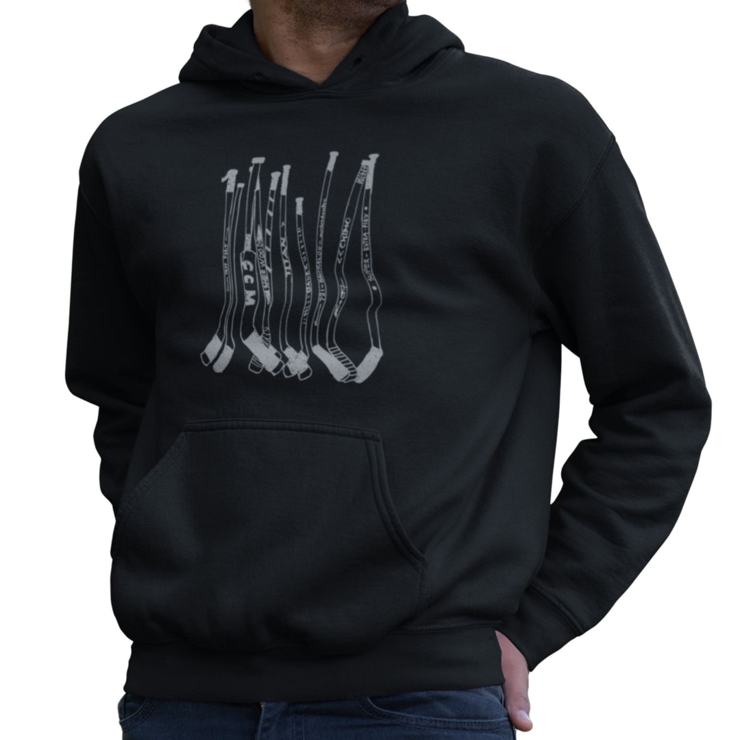 Homme portant un hoodie KM54 noir avec un motif de bâtons de hockey