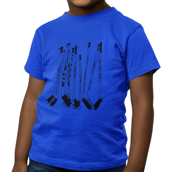 Enfant portant un t-shirt KM54 bleu royal avec un motif de bâtons de hockey noirs