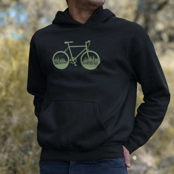 Homme portant une veste à capuchon noire avec un vélo vert ayant une foret  à l'intérieur